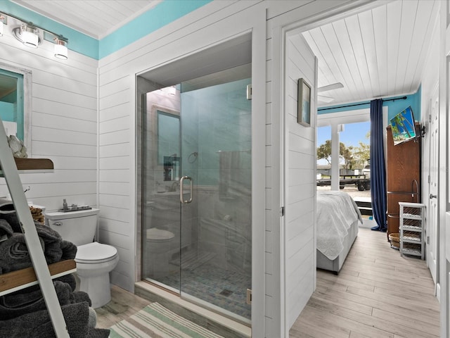 bathroom featuring wooden walls, a shower with door, wood-type flooring, and toilet