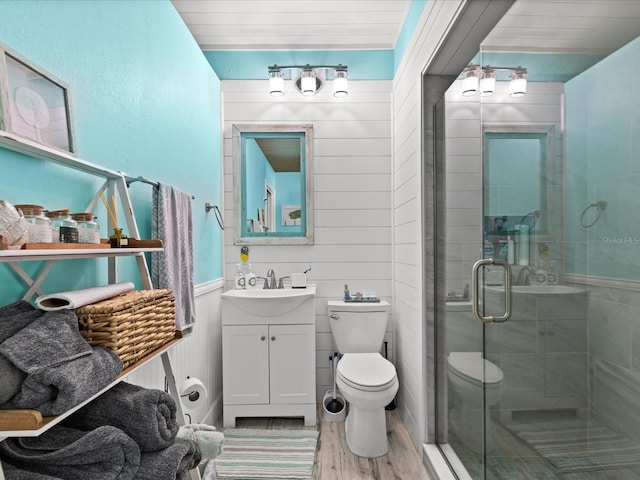 bathroom featuring wood-type flooring, vanity, toilet, and a shower with shower door