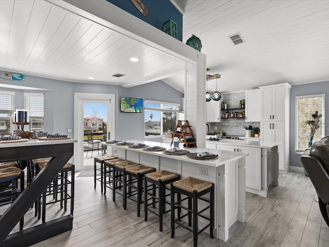 kitchen featuring white cabinets, light hardwood / wood-style floors, a kitchen island, and lofted ceiling