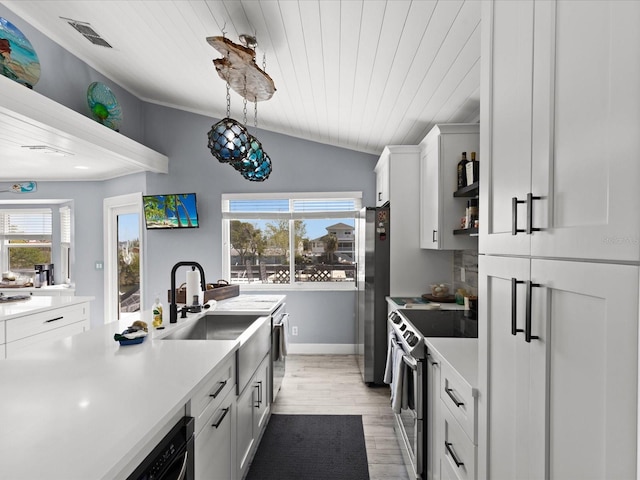 kitchen with a healthy amount of sunlight, white cabinetry, stainless steel appliances, and lofted ceiling