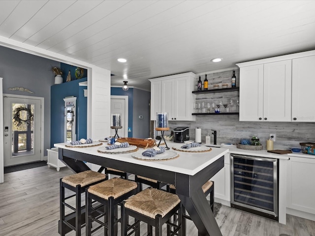 kitchen with white cabinetry, beverage cooler, and light wood-type flooring