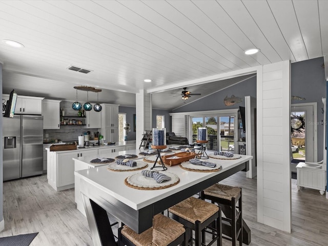 dining space with ceiling fan, wooden ceiling, decorative columns, light hardwood / wood-style floors, and lofted ceiling