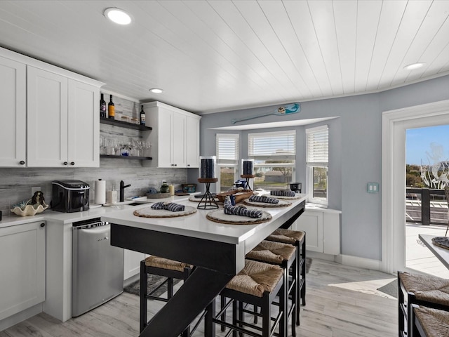 kitchen featuring a breakfast bar area, white cabinetry, and light wood-type flooring