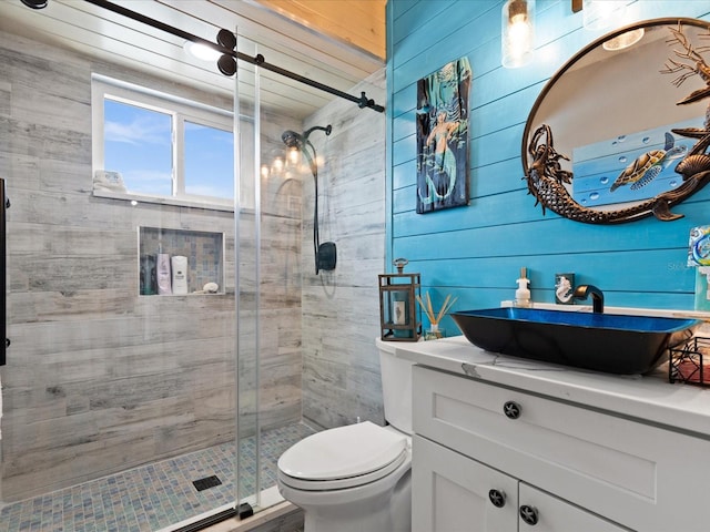 bathroom featuring wooden walls, vanity, a shower with shower door, and toilet