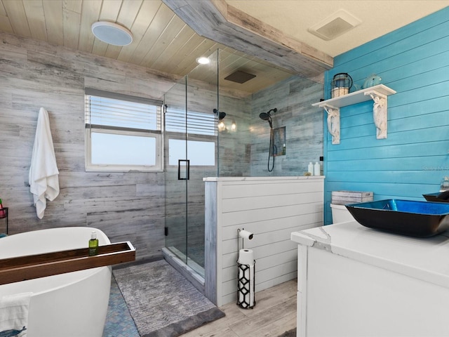 bathroom with vanity, hardwood / wood-style flooring, a shower with shower door, and wood walls