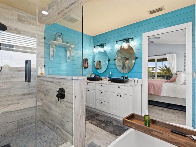 bathroom featuring walk in shower, hardwood / wood-style floors, lofted ceiling, wooden walls, and vanity