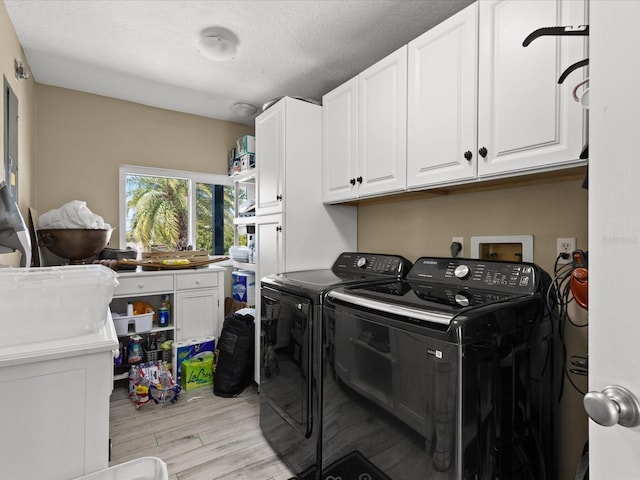 laundry area with cabinets, washer and clothes dryer, light hardwood / wood-style floors, and a textured ceiling