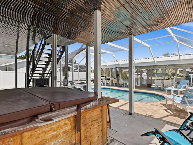 view of swimming pool with a lanai, a patio area, and a hot tub