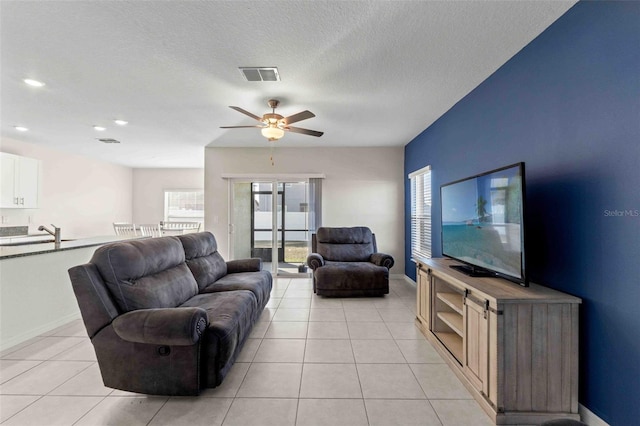 tiled living room featuring ceiling fan and a textured ceiling