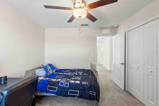 carpeted bedroom featuring ceiling fan, a closet, and a textured ceiling