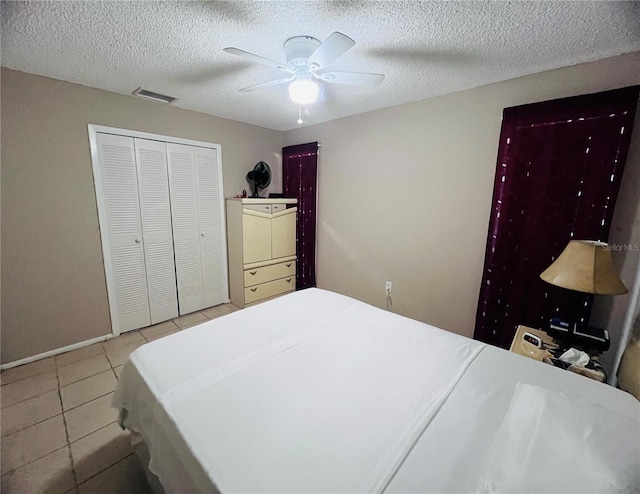 tiled bedroom featuring ceiling fan, a closet, and a textured ceiling