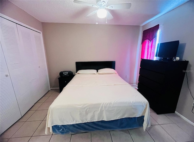 tiled bedroom with ceiling fan, a closet, and a textured ceiling