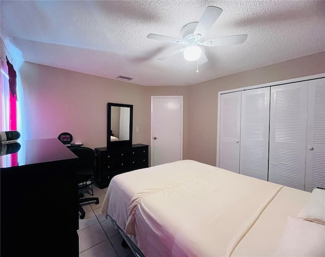 tiled bedroom with ceiling fan, a closet, and a textured ceiling