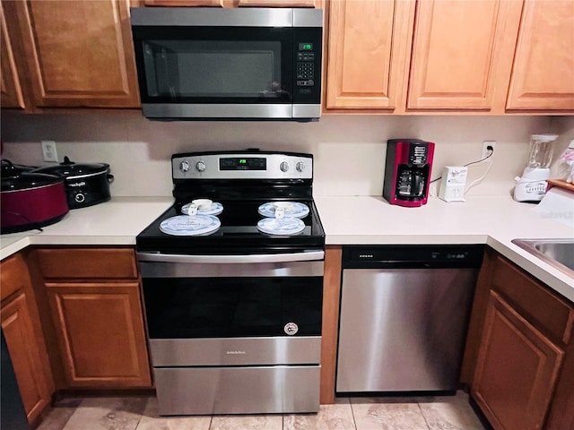 kitchen with appliances with stainless steel finishes, light tile patterned floors, and sink