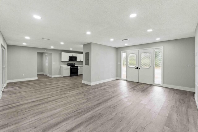 unfurnished living room featuring french doors, a textured ceiling, electric panel, and light hardwood / wood-style flooring