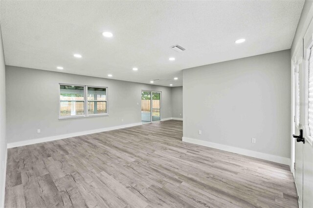 spare room featuring a textured ceiling and light hardwood / wood-style flooring