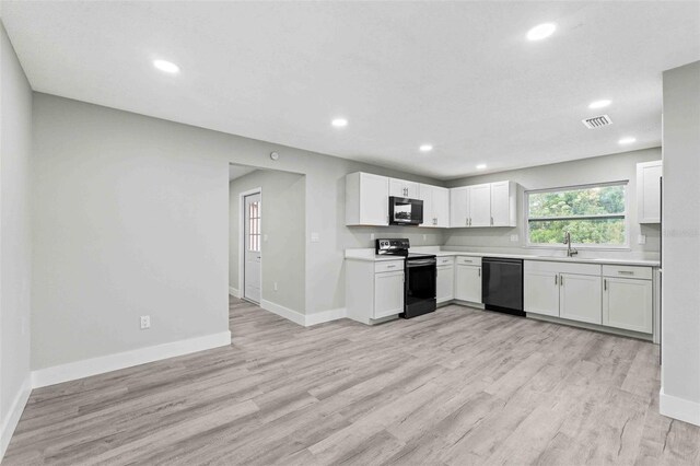 kitchen with white cabinetry, sink, black appliances, and light wood-type flooring