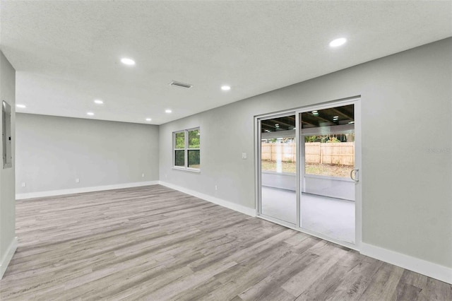 empty room with light hardwood / wood-style flooring and a textured ceiling