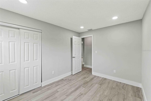 unfurnished bedroom featuring a closet, a textured ceiling, and light wood-type flooring