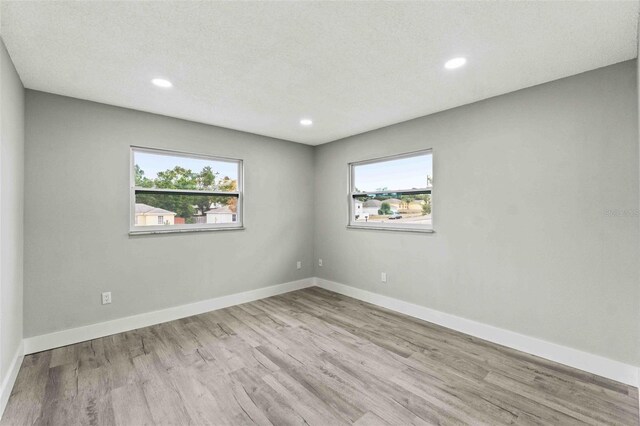 empty room with light hardwood / wood-style floors and a textured ceiling