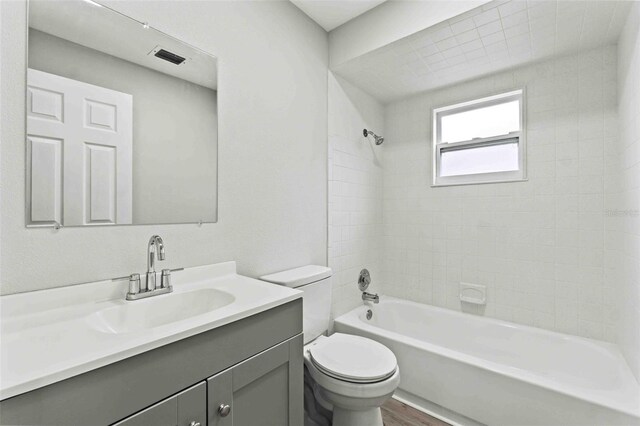 full bathroom featuring wood-type flooring, vanity, toilet, and tiled shower / bath