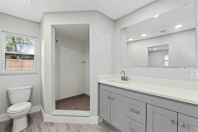 bathroom featuring tiled shower, vanity, wood-type flooring, and toilet