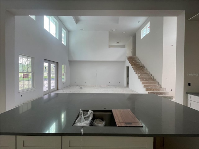 kitchen featuring a towering ceiling, white cabinets, and french doors