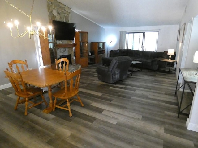 dining space with dark hardwood / wood-style floors, lofted ceiling, a fireplace, and an inviting chandelier