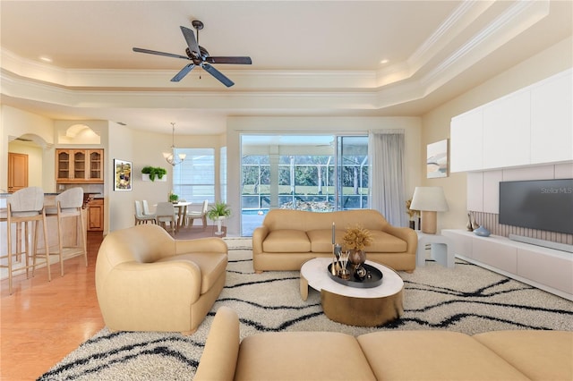 living room with ceiling fan with notable chandelier, light hardwood / wood-style floors, a raised ceiling, and crown molding