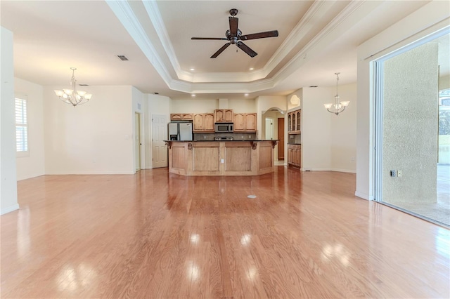 kitchen with stainless steel appliances, a raised ceiling, crown molding, light hardwood / wood-style floors, and decorative light fixtures