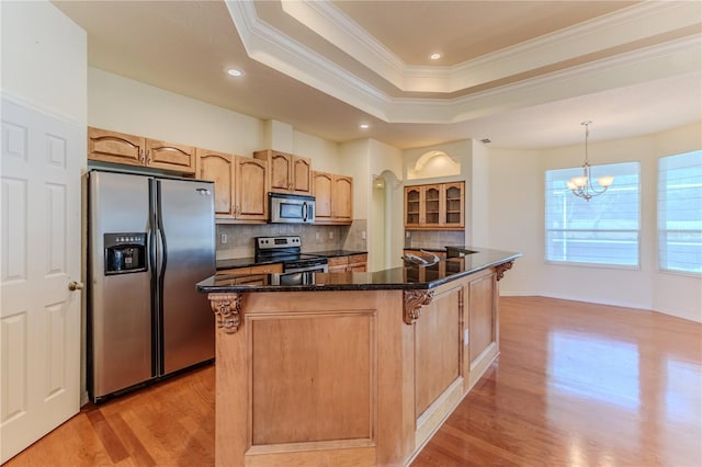 kitchen featuring backsplash, light hardwood / wood-style floors, appliances with stainless steel finishes, decorative light fixtures, and a kitchen island