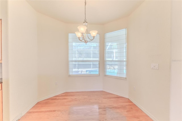 unfurnished dining area with an inviting chandelier and light hardwood / wood-style flooring