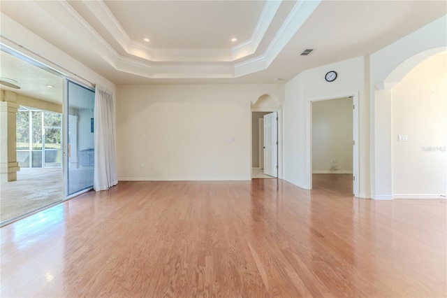 unfurnished room featuring light wood-type flooring, a tray ceiling, and ornamental molding