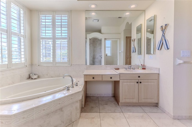 bathroom with tile patterned flooring, plenty of natural light, a relaxing tiled tub, and vanity