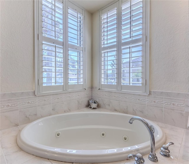 bathroom with a relaxing tiled tub and a healthy amount of sunlight