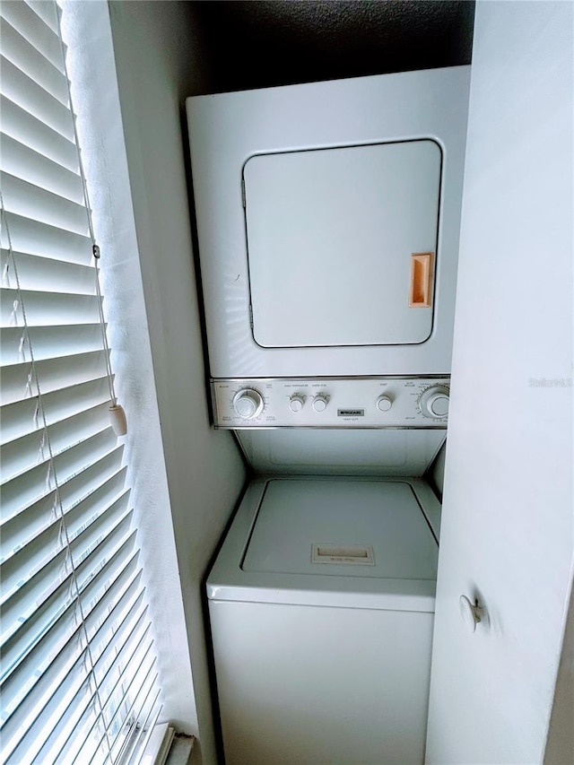 clothes washing area featuring stacked washing maching and dryer