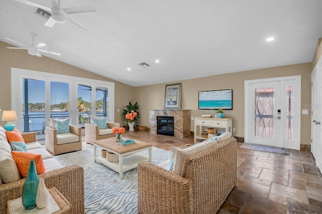 living room with ceiling fan, french doors, a high end fireplace, and vaulted ceiling