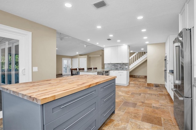 kitchen with gray cabinetry, wood counters, white cabinetry, and stainless steel appliances