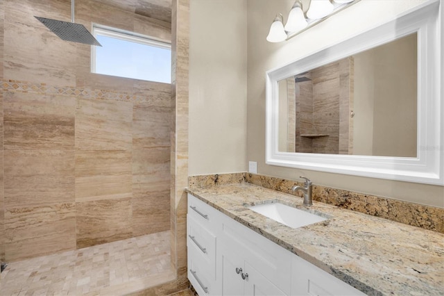 bathroom with a tile shower and vanity