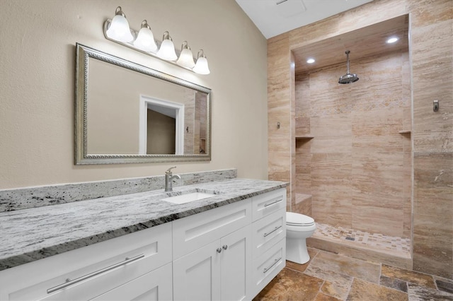 bathroom with vanity, toilet, and a tile shower