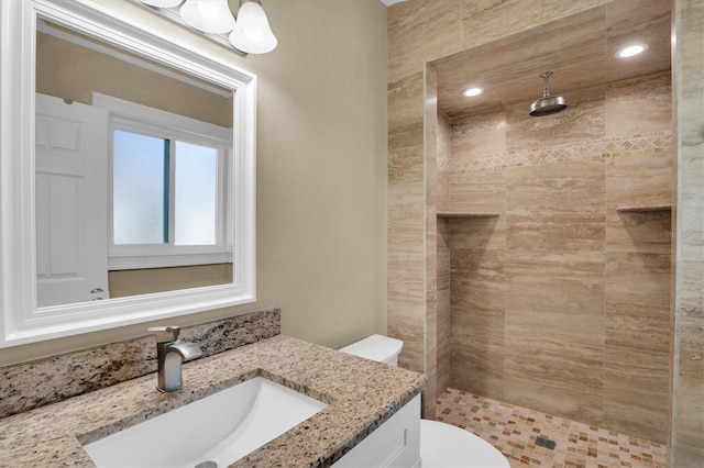 bathroom featuring vanity, toilet, and tiled shower