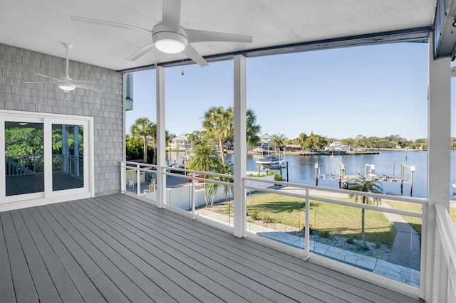 wooden terrace featuring ceiling fan, a water view, and a boat dock