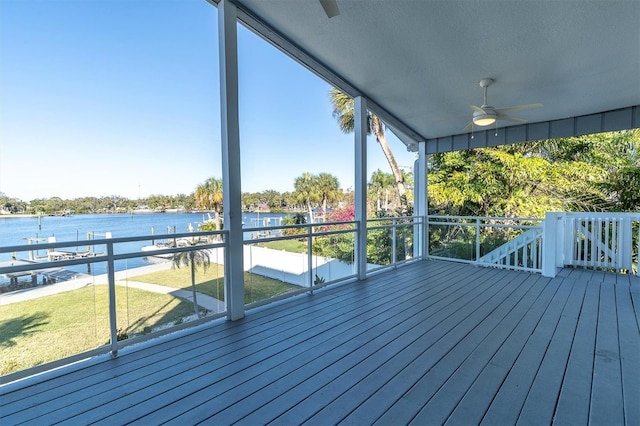 deck with a water view, ceiling fan, and a lawn