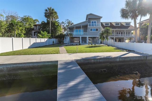 view of dock featuring a lawn and a balcony