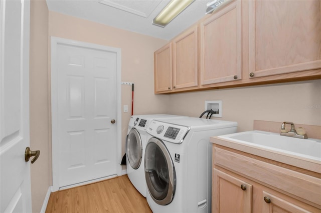 washroom with light hardwood / wood-style floors, sink, cabinets, and independent washer and dryer