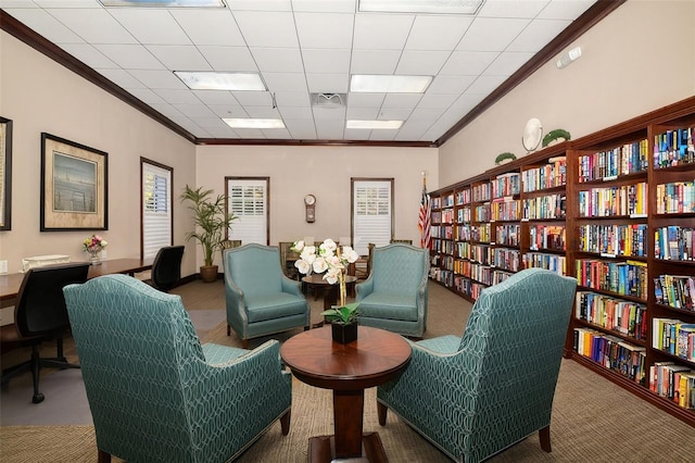 living area featuring carpet floors, a drop ceiling, and ornamental molding