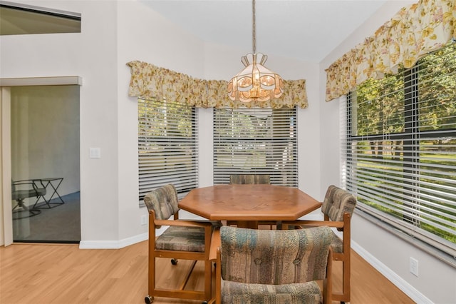 dining room featuring hardwood / wood-style floors, lofted ceiling, and an inviting chandelier