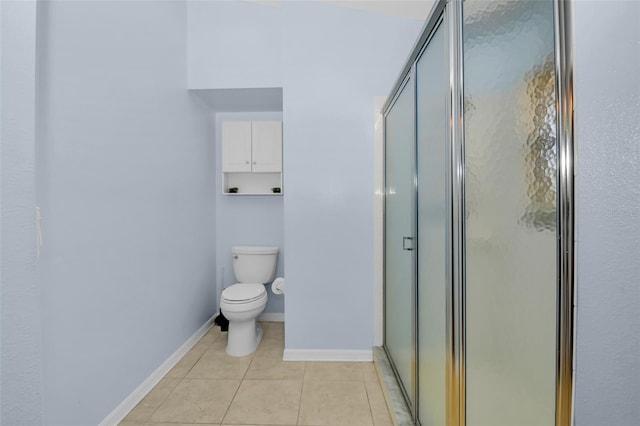 bathroom featuring tile patterned flooring, toilet, and a shower with door