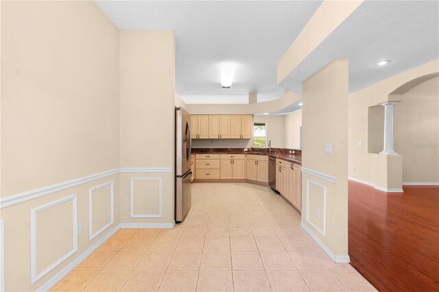 4201 Silver Berry Ct, Spring Hill, FL 34609 - kitchen featuring stainless steel appliances, decorative columns, dark countertops, arched walkways, and light brown cabinetry
