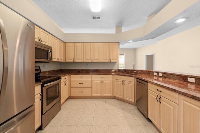 kitchen featuring sink, stainless steel appliances, a textured ceiling, light brown cabinetry, and light tile patterned floors